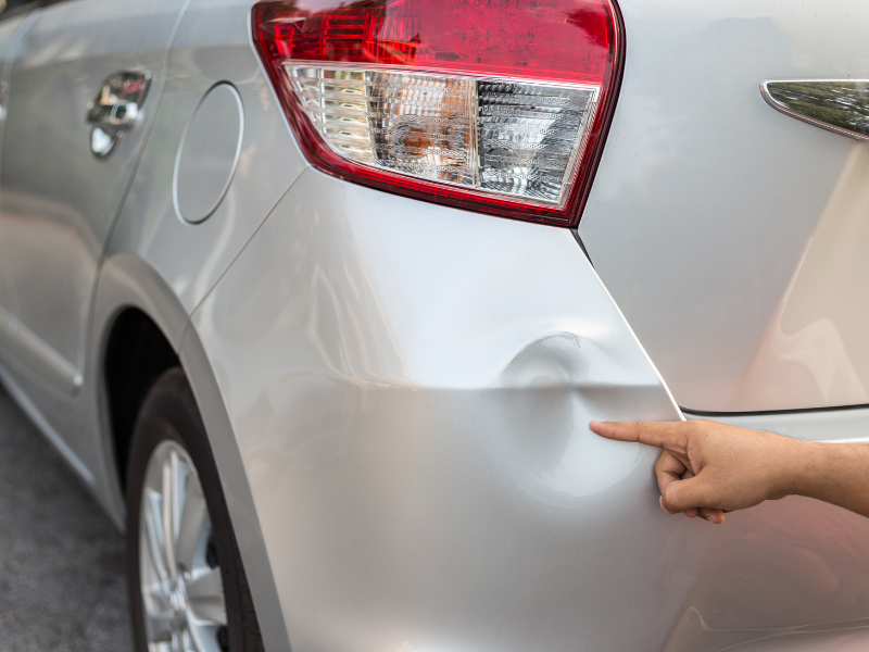 a dent in a silver car bumper