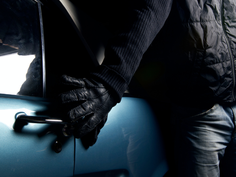 a person trying to break into a car at night